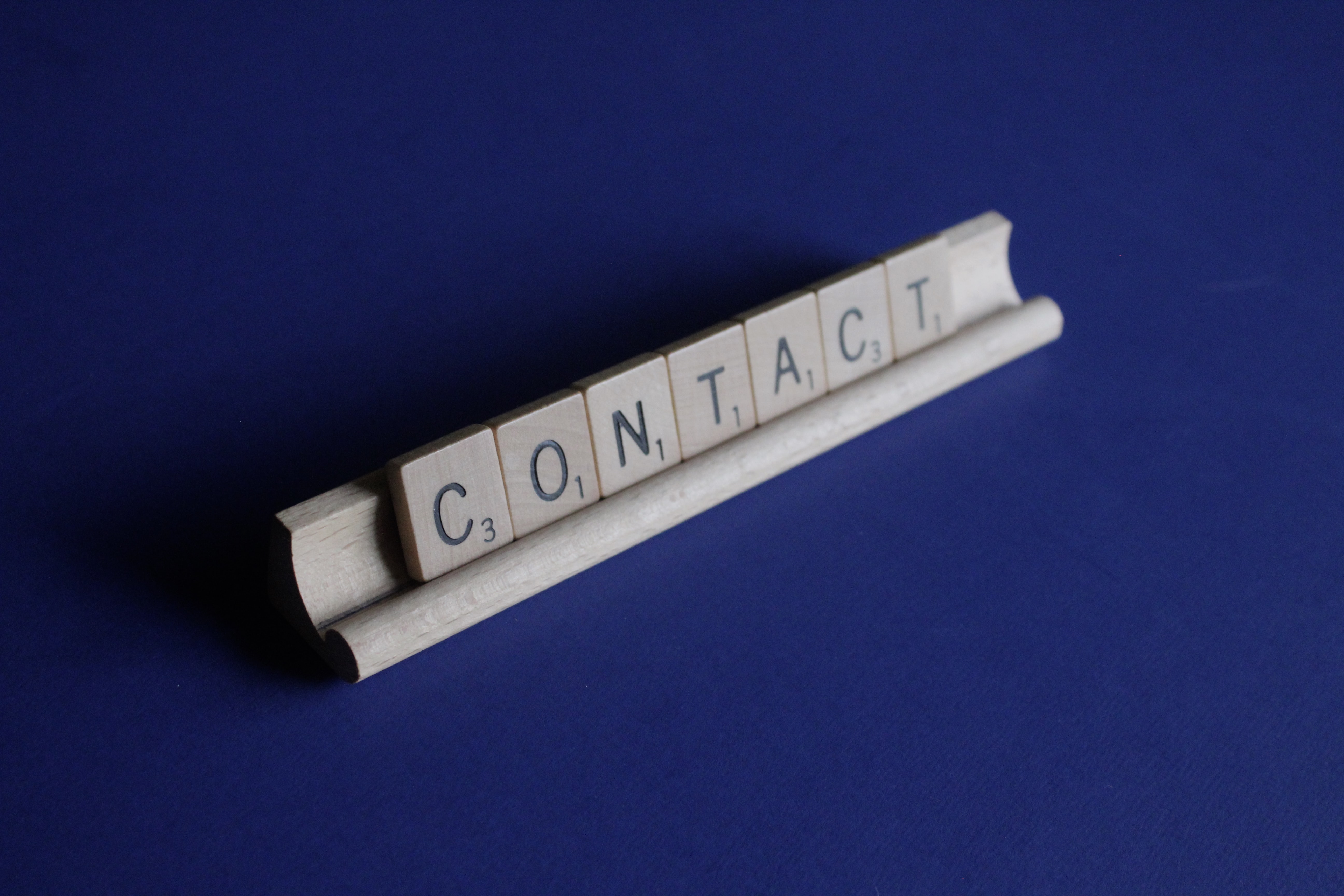 Contact spelled using scrabble tiles, blue background